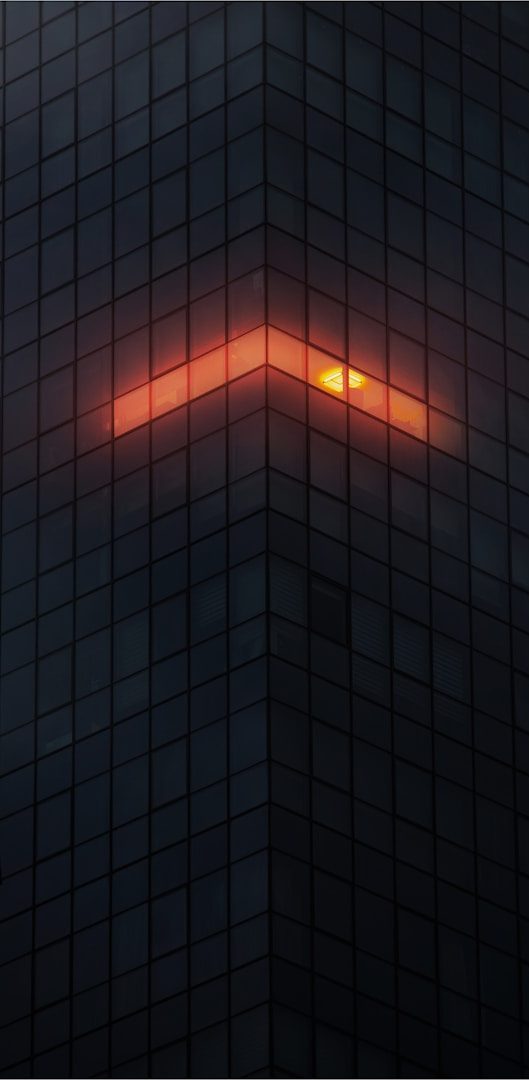 Picture of a building for design purposes A diagonal orange light reflecting on a dark glass building corner.