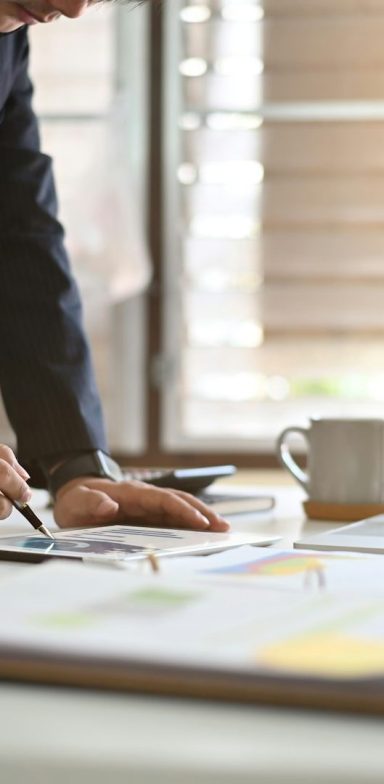Conducting an Audit A person analysing documents with a cup and sketches on a table.