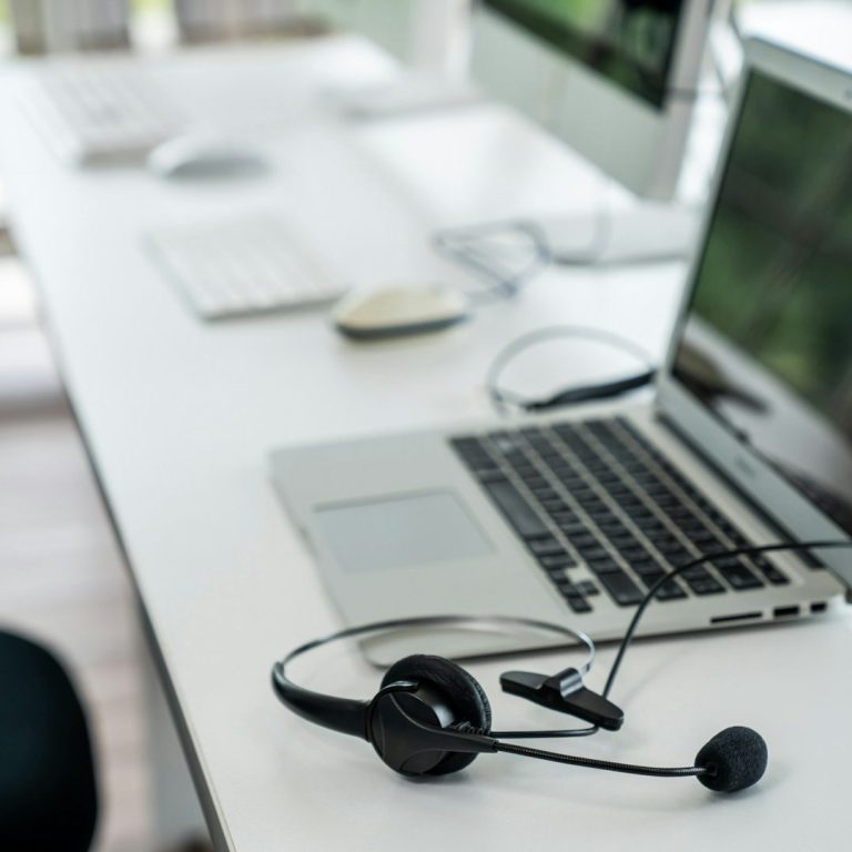 IT Support Laptop with a headset on a desk, beside a keyboard and mouse.