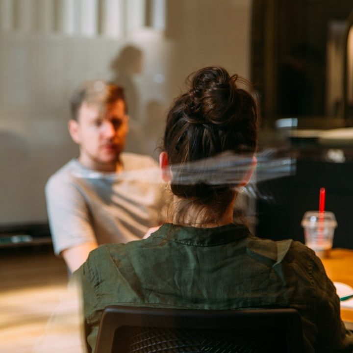 IT Consultancy Two people engaged in a discussion at a table, with a drink nearby.